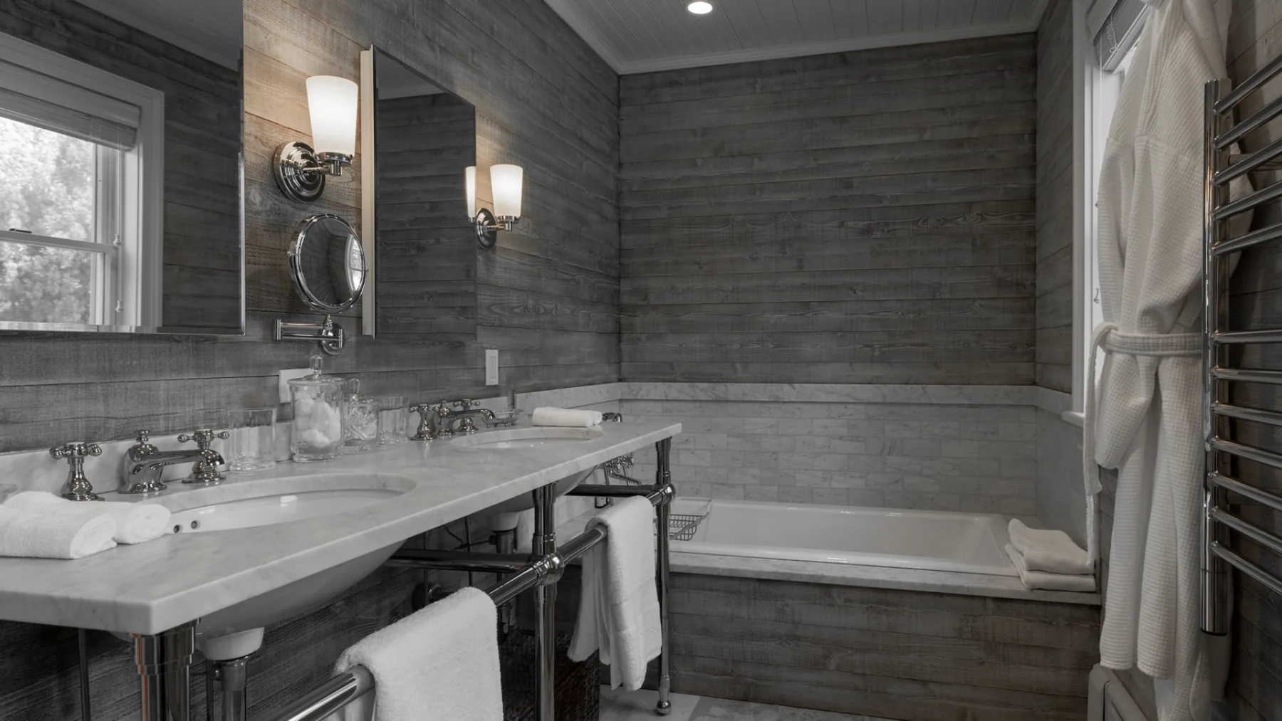 A bathroom with a long vanity, wall mirror, and bathtub.
