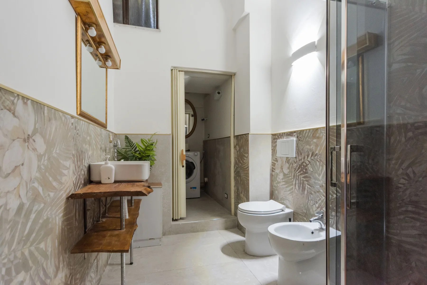 Un baño luminoso con lavabo, inodoro, bidé y ducha de vidrio.