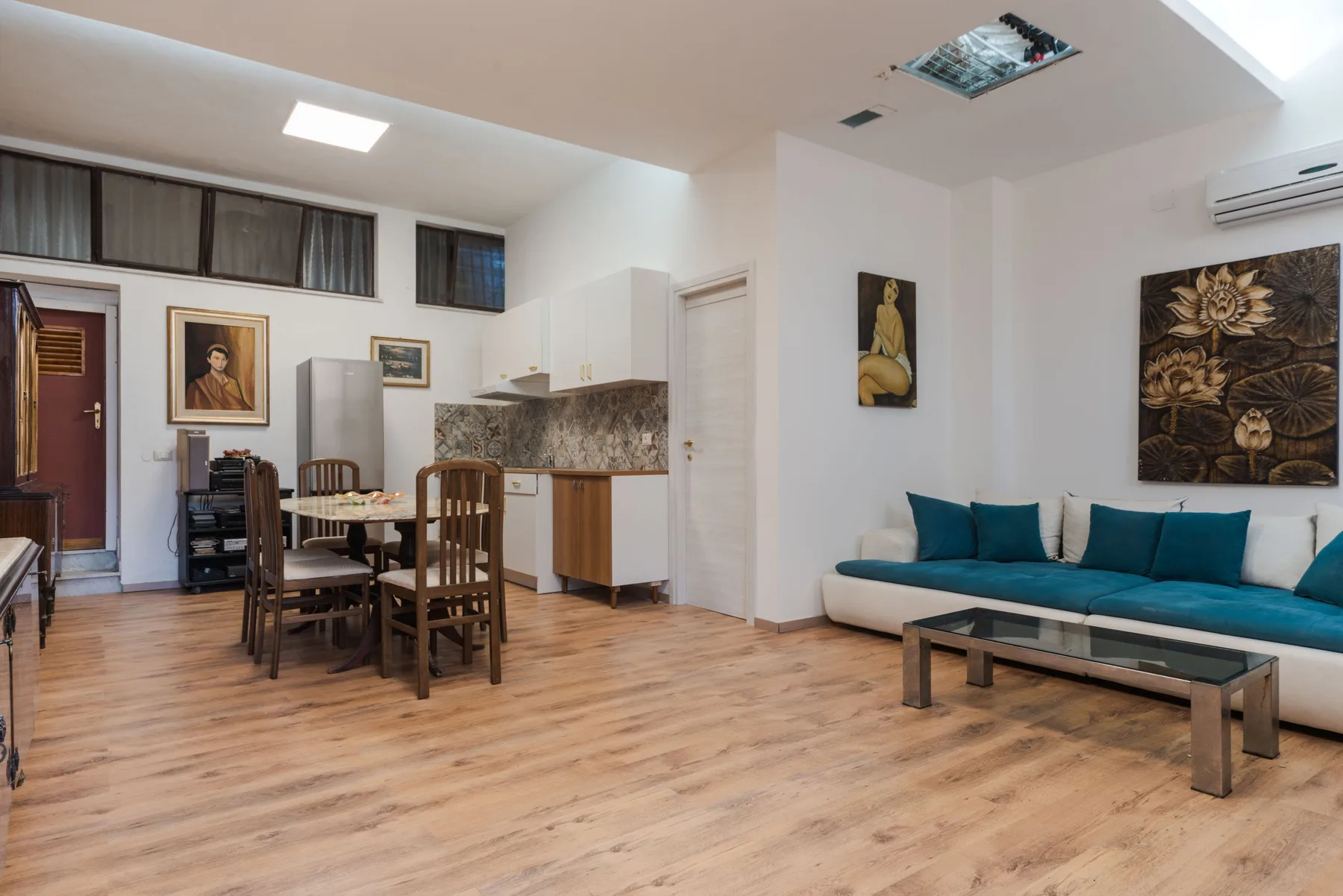 Una sala de estar y comedor con un sofá turquesa y una mesa de comedor de madera.