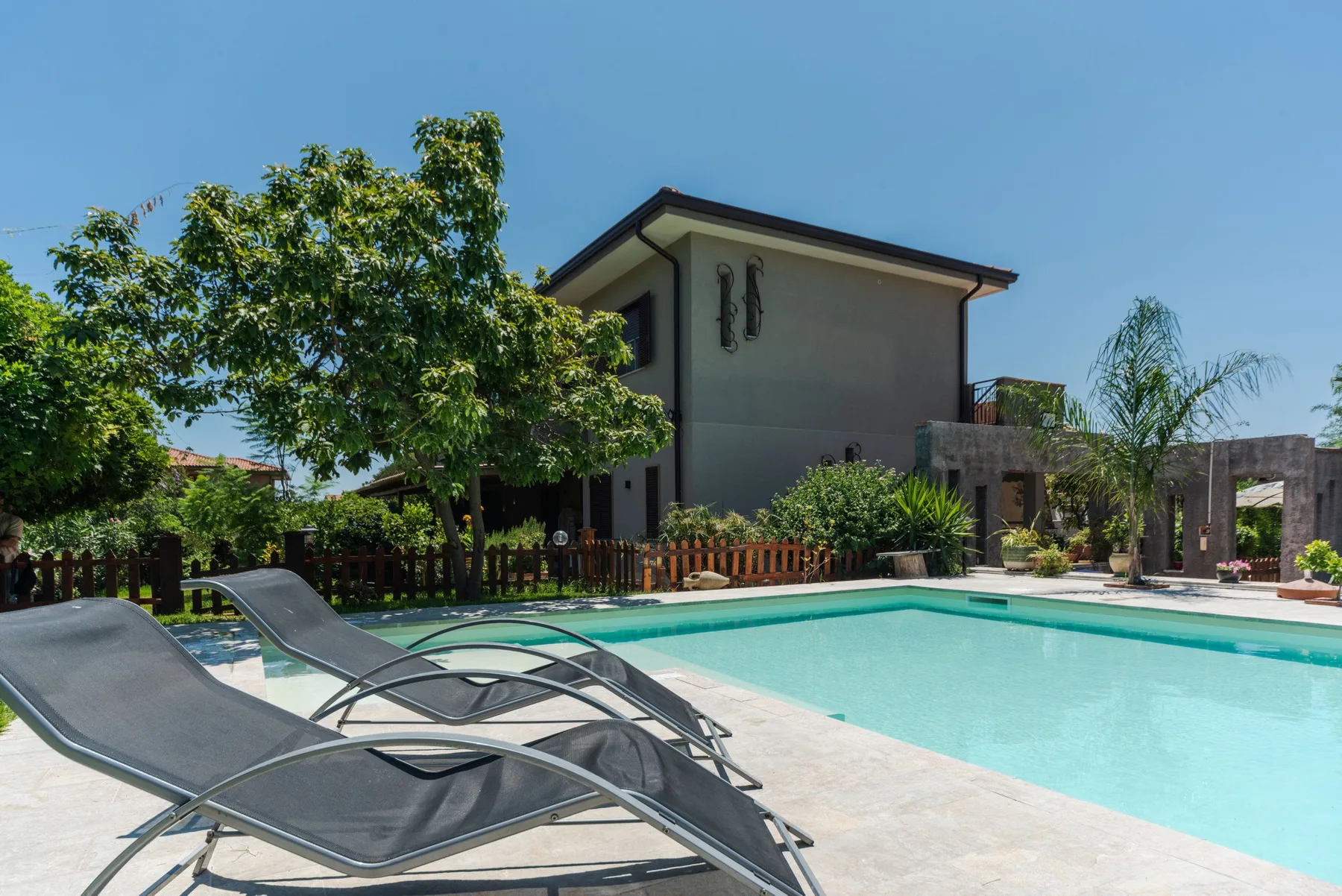 Una piscina al aire libre junto a una casa moderna y asientos de descanso.