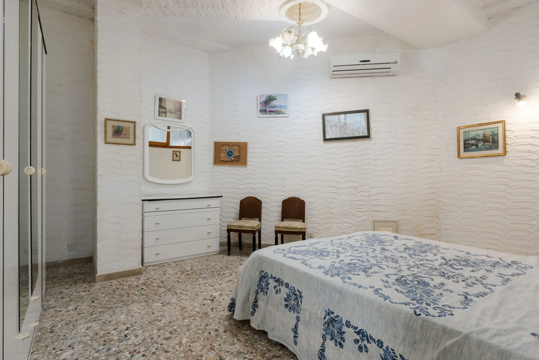 Un dormitorio con una cama cubierta con ropa de cama floral azul y una cómoda.