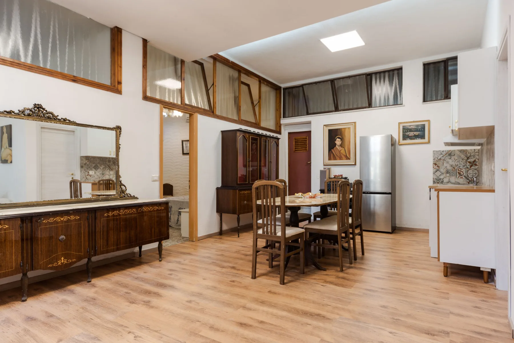 Un comedor con una mesa y sillas de madera junto a electrodomésticos de cocina.