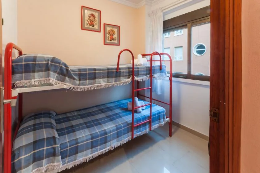 A bedroom with a blue plaid bunk bed beside a window.