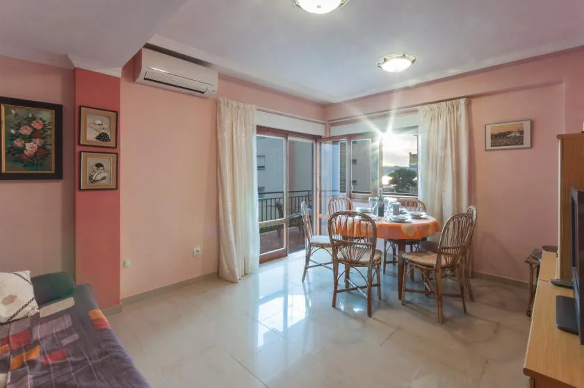 A dining area with a table and chairs beside glass doors opening onto a balcony.