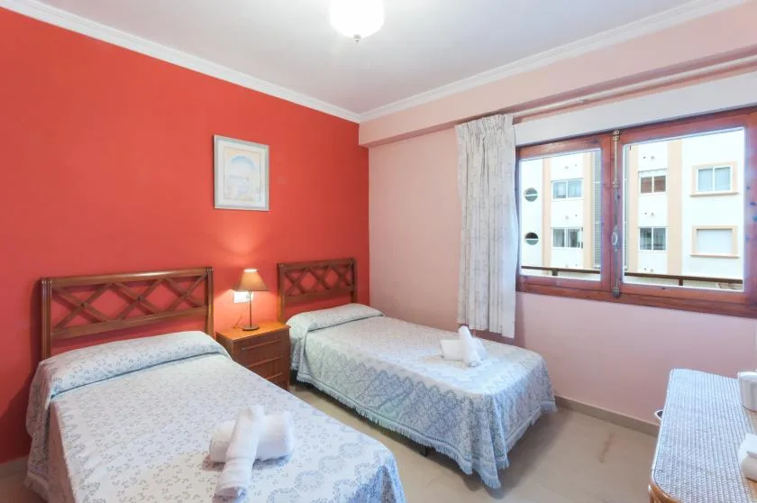A twin bedroom with two beds beside a large window.