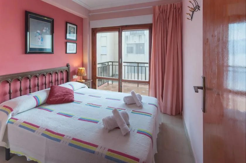 A bedroom with a neatly made bed and sliding glass doors opening onto a balcony.