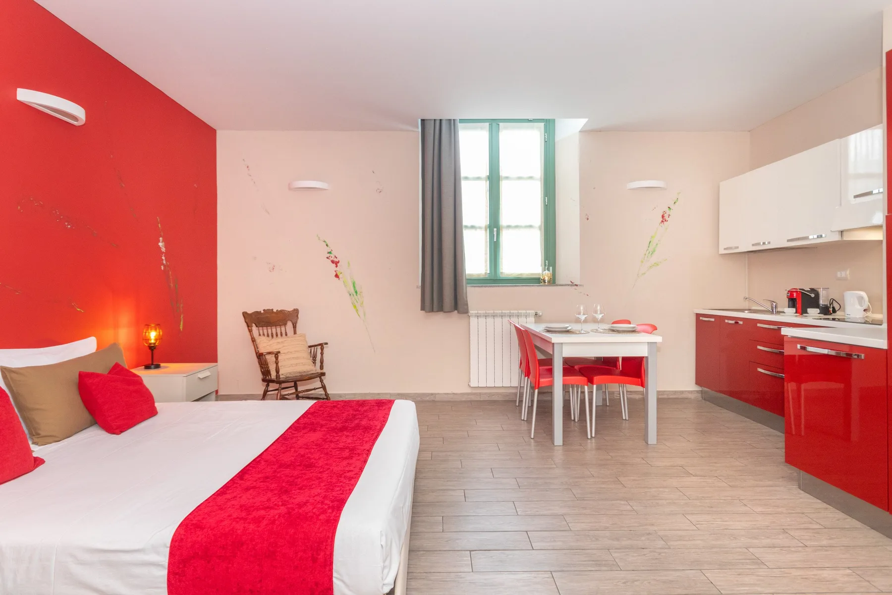 A bedroom and kitchenette share a bright room, with a bed and dining table.