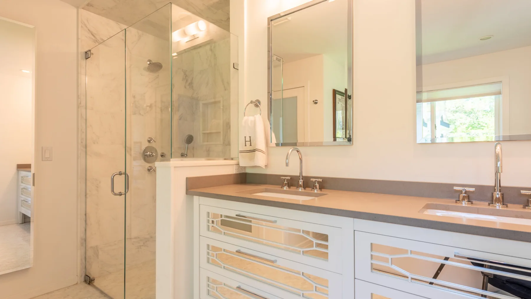 Un tocador de baño con dos lavabos está junto a una ducha de vidrio.