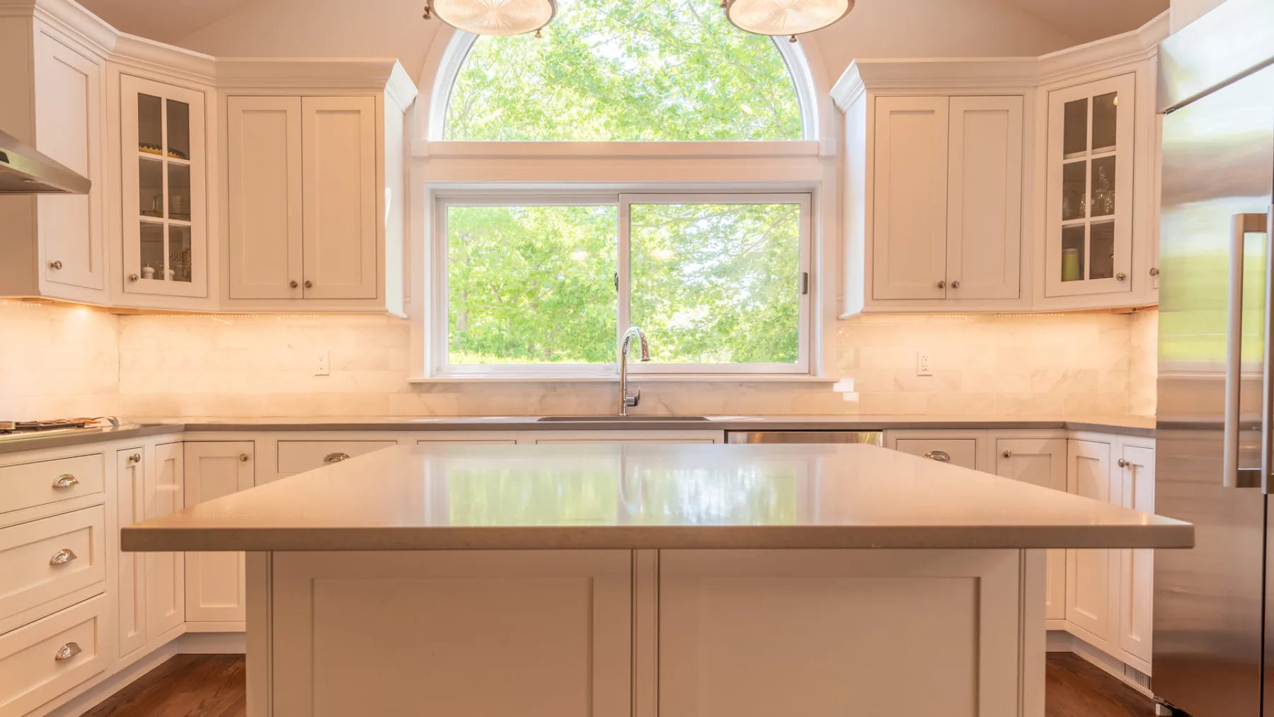 Una cocina luminosa con gabinetes claros, una isla central y una ventana grande.