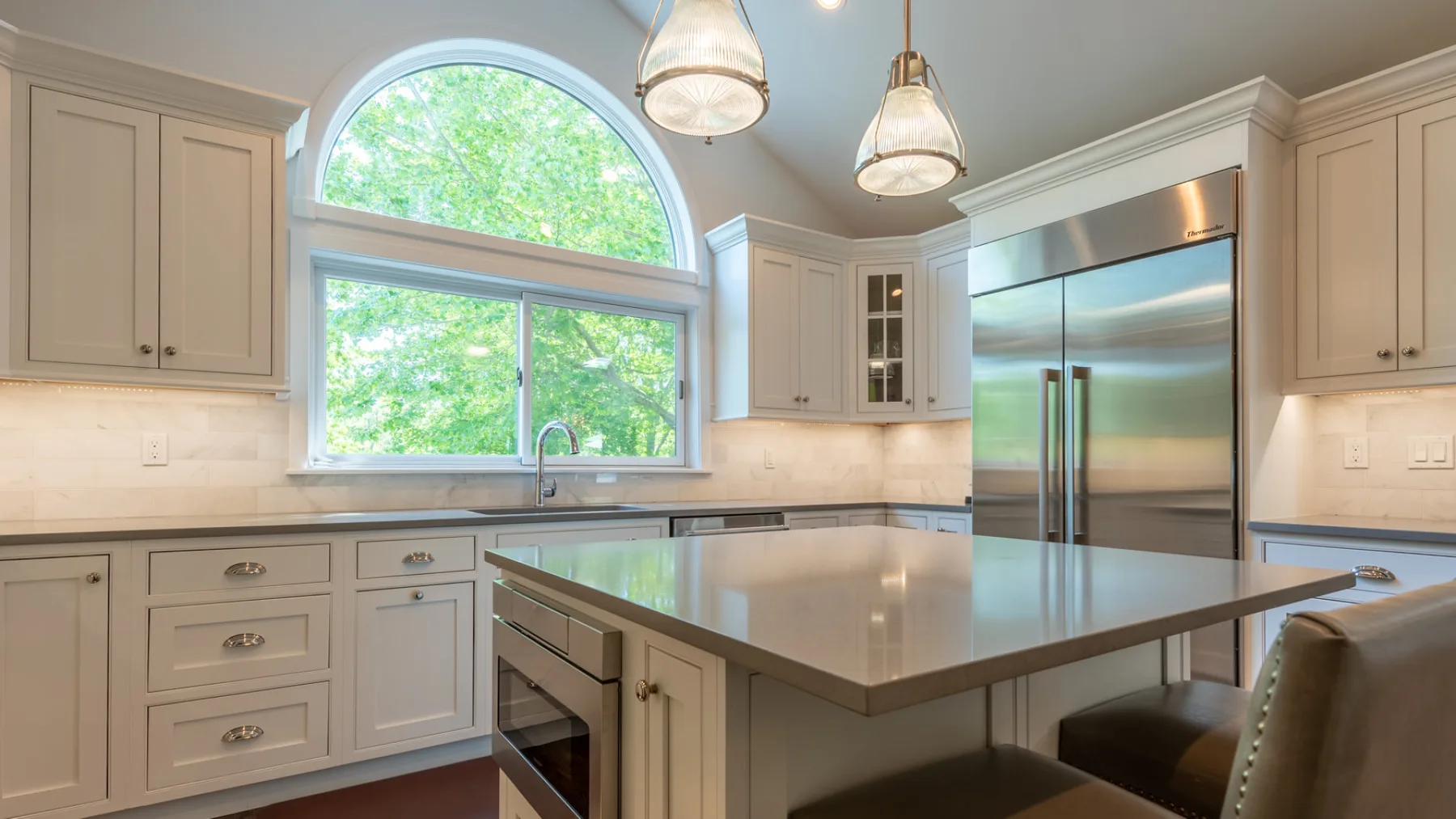 Una cocina luminosa con una gran isla central y un refrigerador de acero inoxidable.