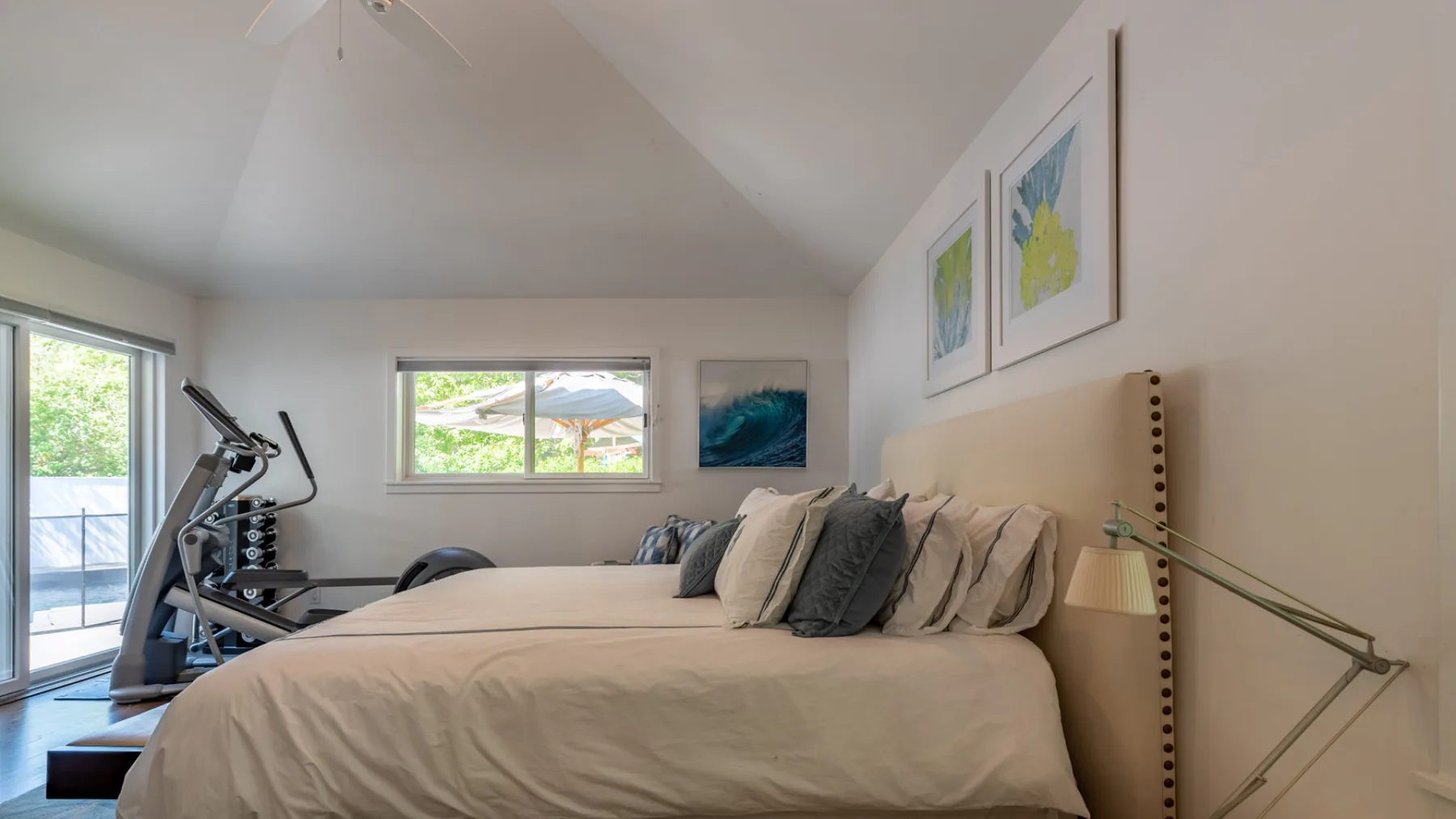Un dormitorio con una cama grande y equipo de ejercicio junto a la ventana.