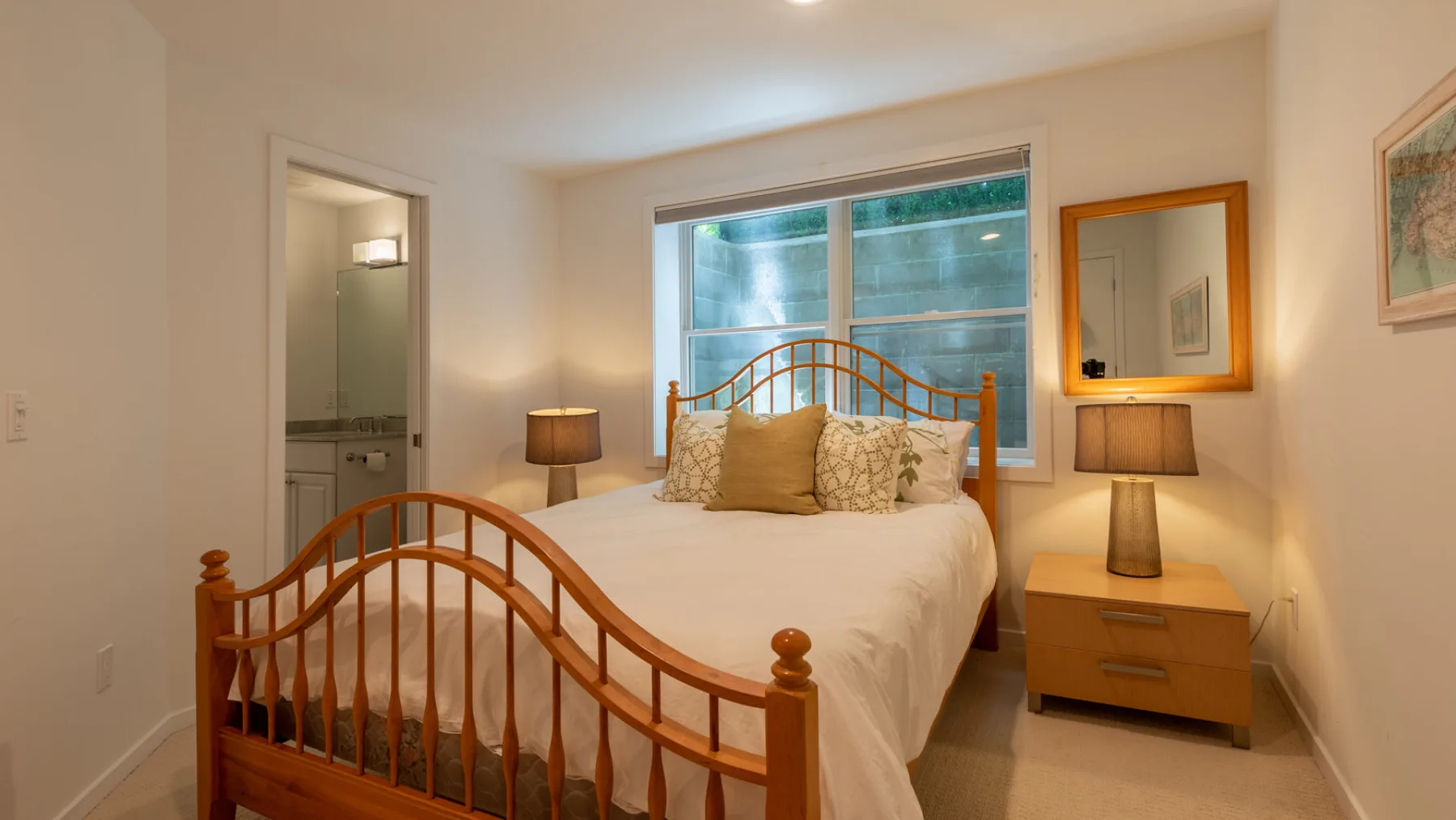 Un dormitorio con una cama de madera, mesitas de noche y una ventana grande.