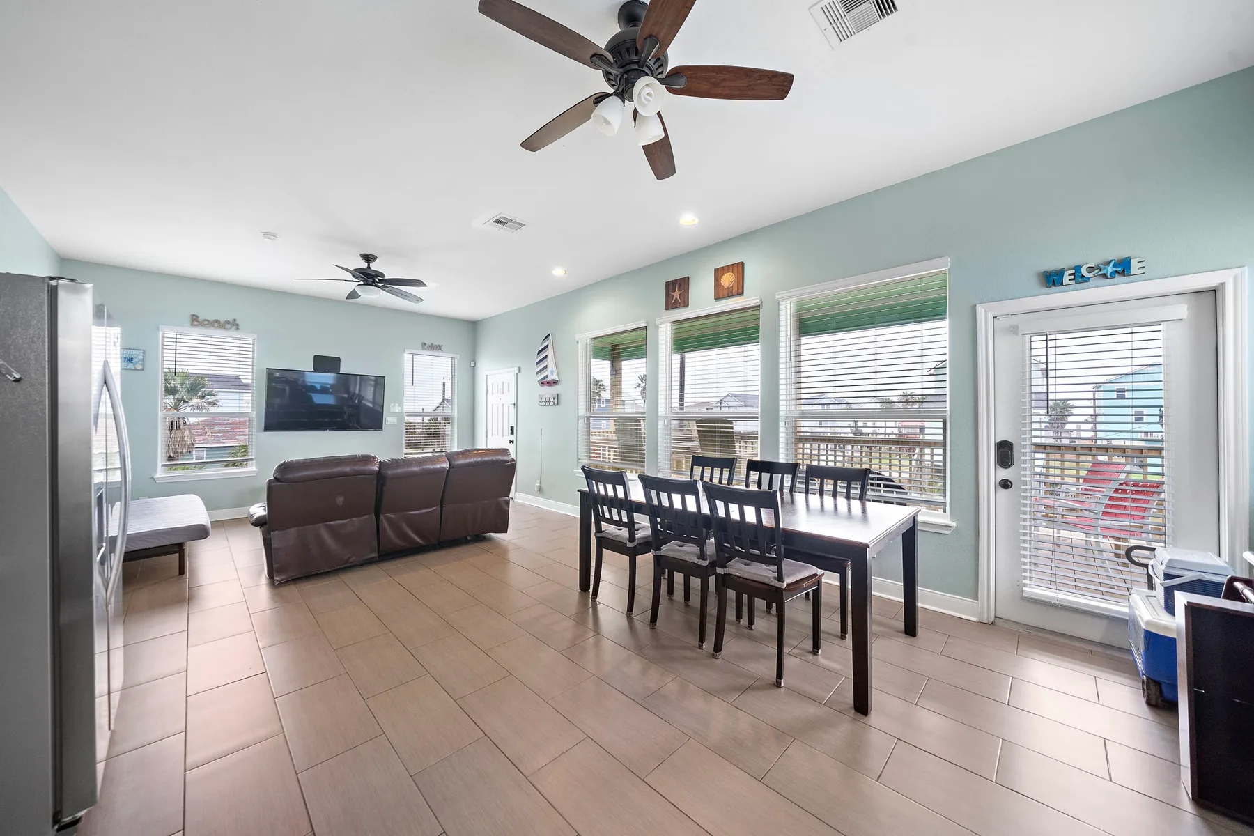A bright dining and living area with a dining table beside large windows.