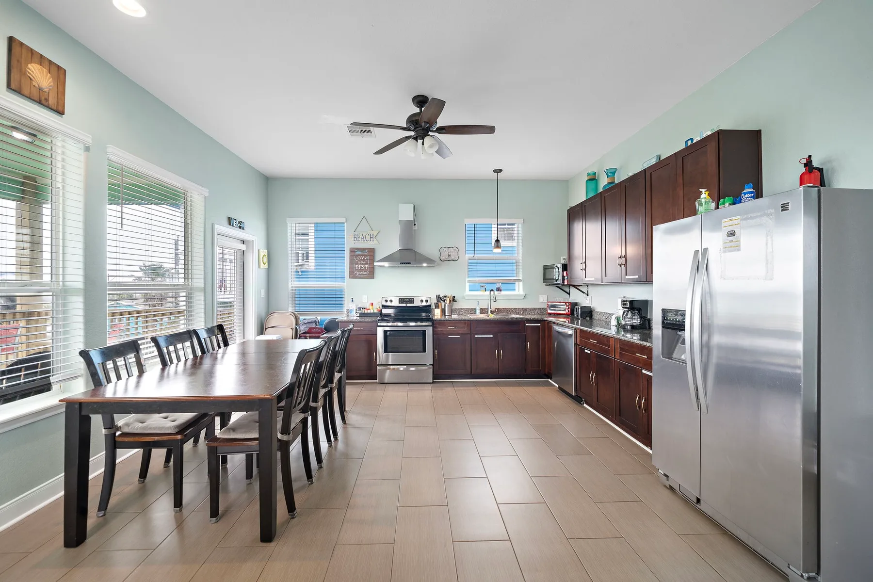 A spacious kitchen and dining area with dark cabinets and a long table.