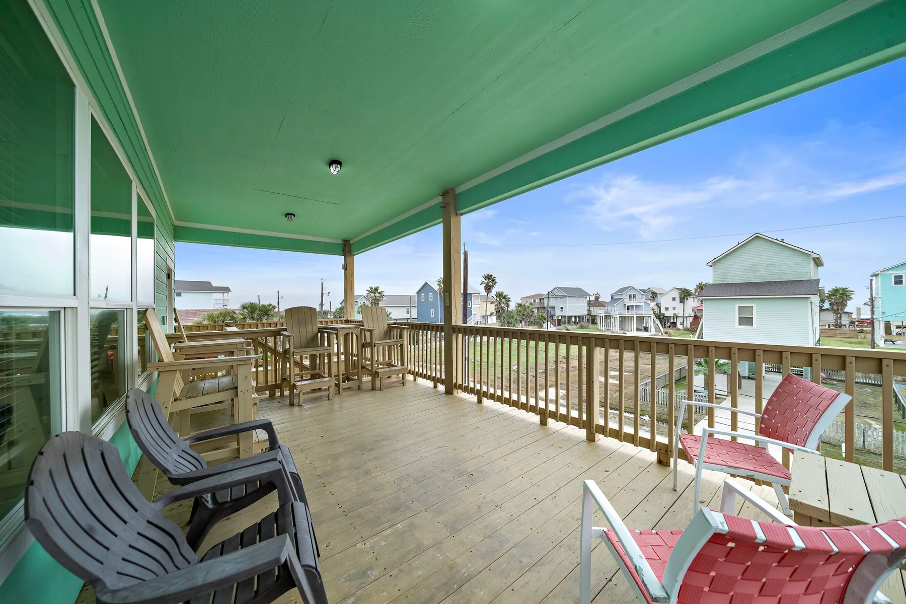 A covered wooden deck overlooks nearby houses, with seating along the railing.