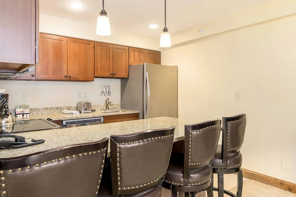 A kitchen with wooden cabinets, stainless steel appliances, and seating at the counter.