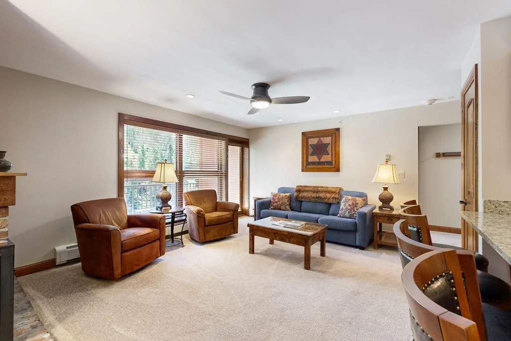 A living room with seating around a coffee table and large windows.