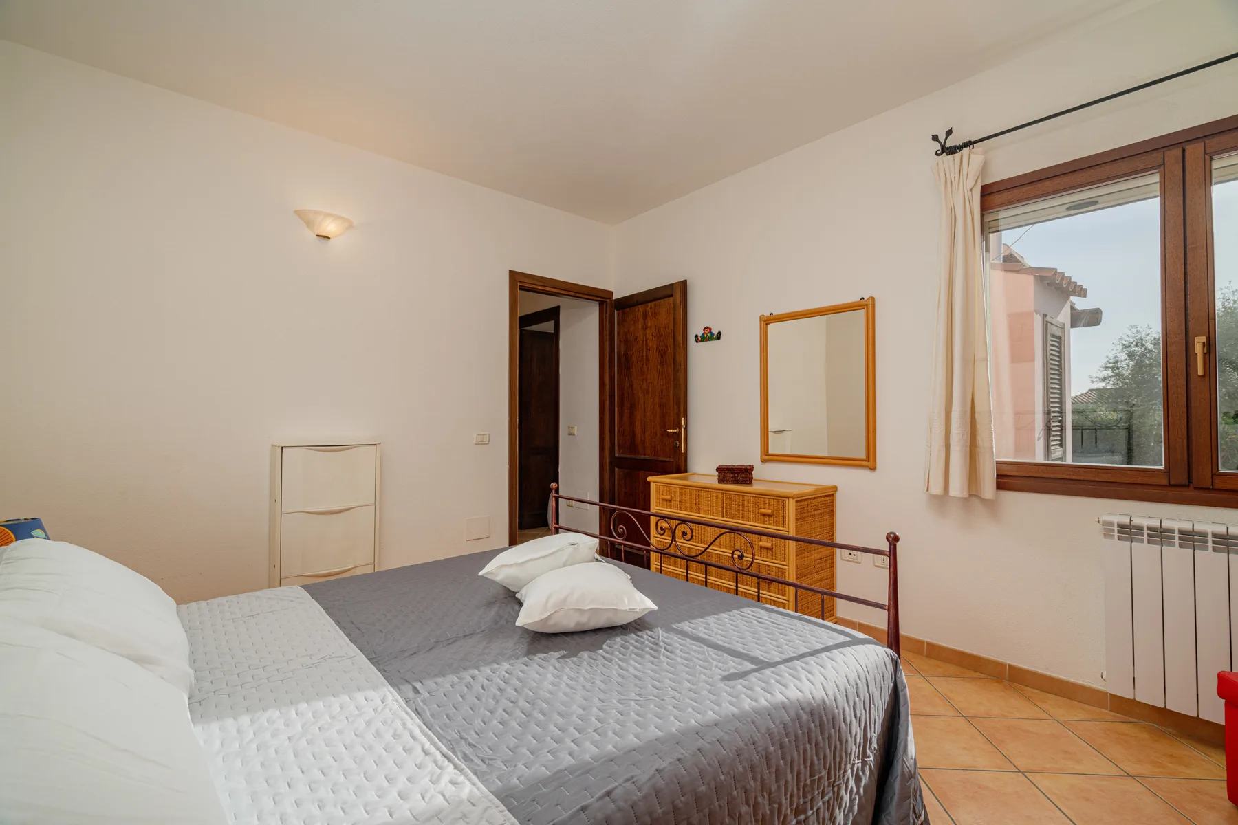 Un dormitorio con una cama, una cómoda de madera y una ventana.