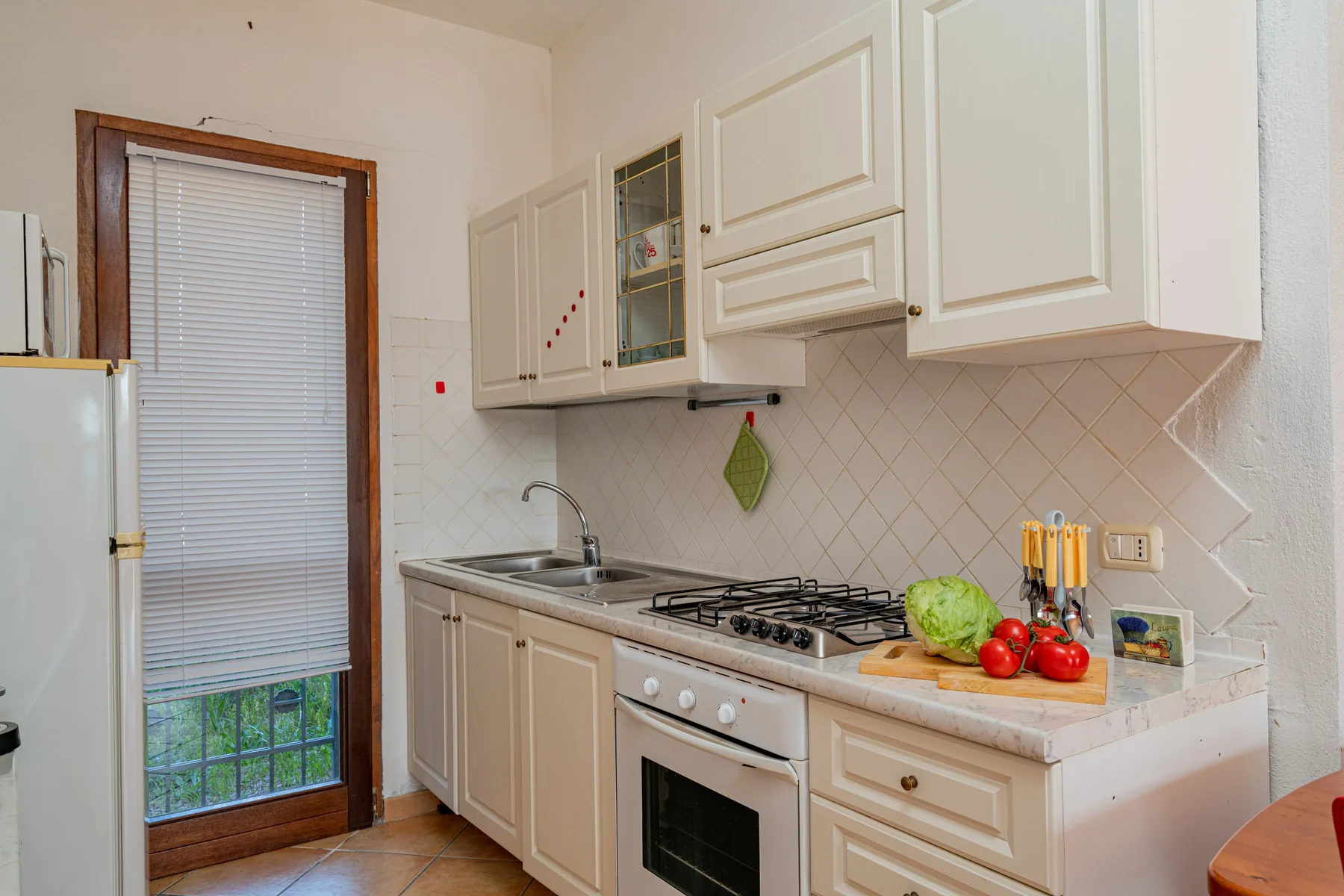 Una cocina compacta con gabinetes blancos, estufa y encimera.