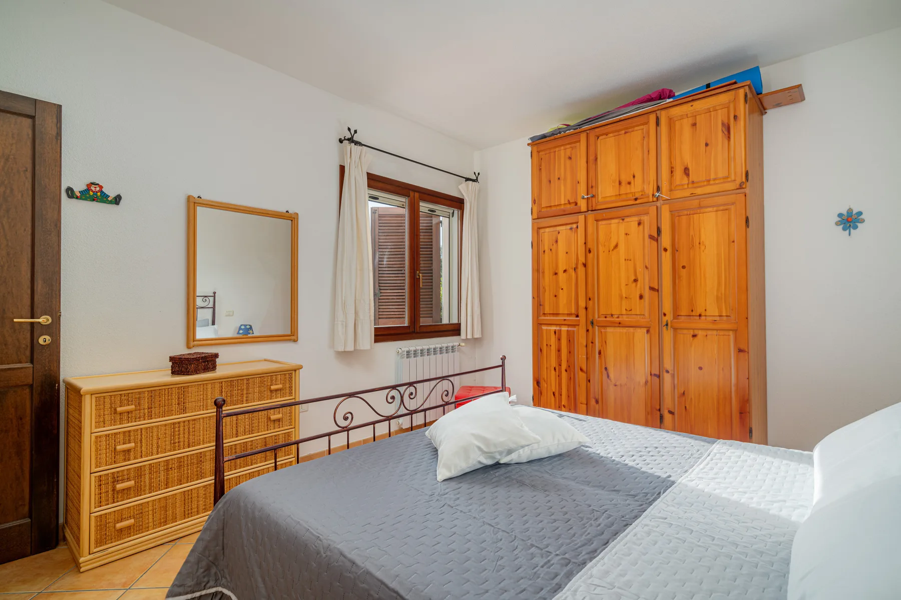 Un dormitorio con una cama, un armario de madera y una ventana.