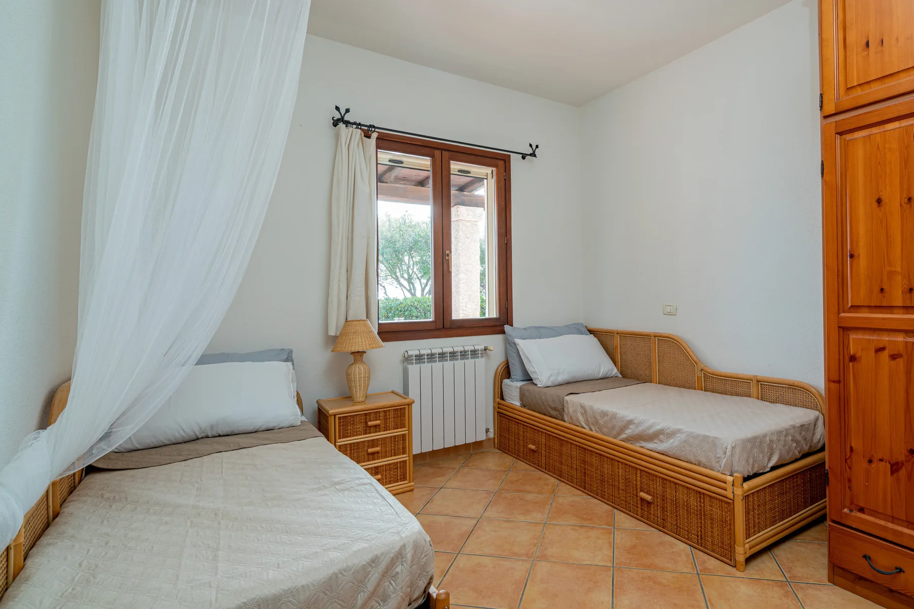 Un dormitorio con dos camas, una ventana y un armario de madera.