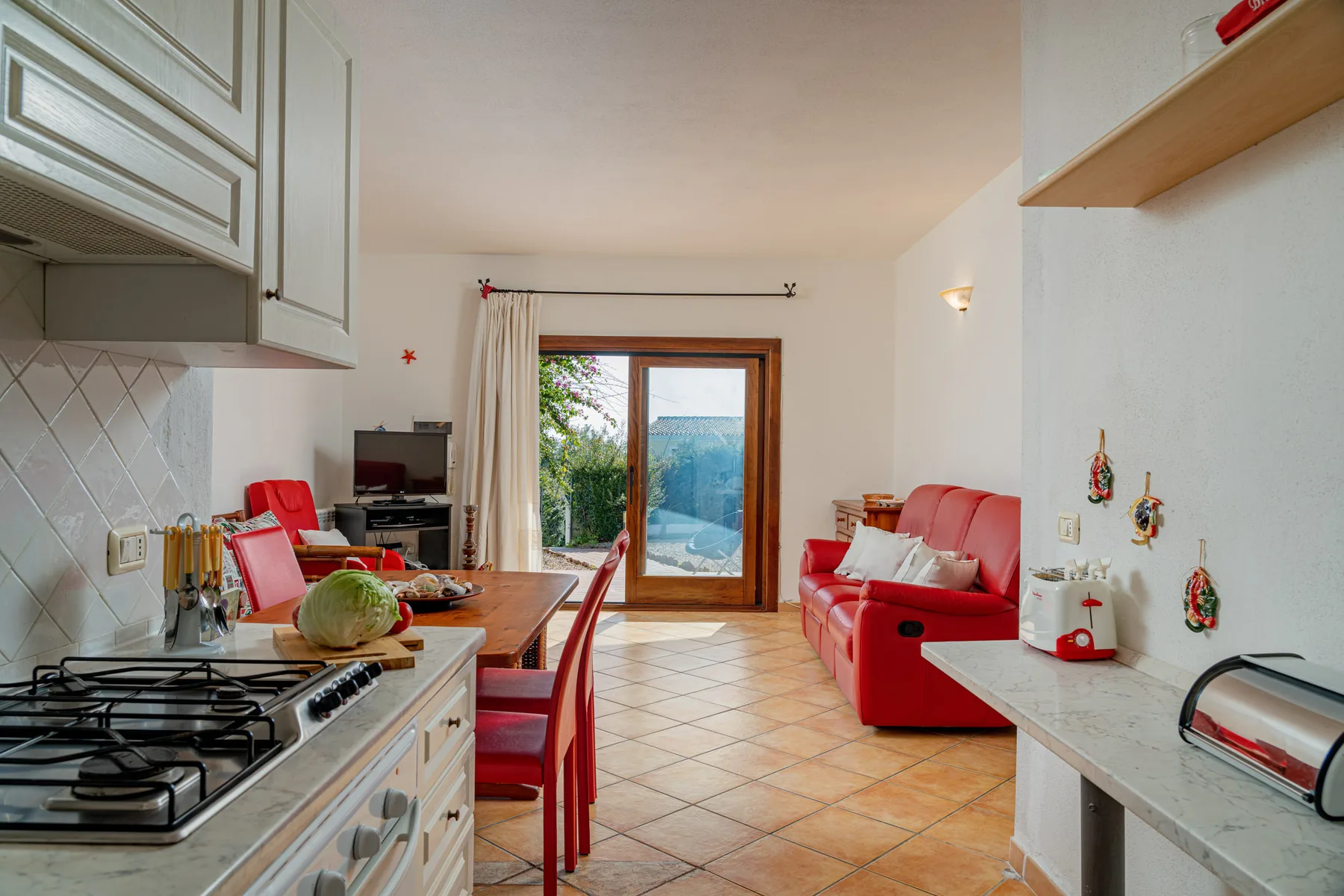 La cocina y el comedor se abren a una sala luminosa con asientos rojos.