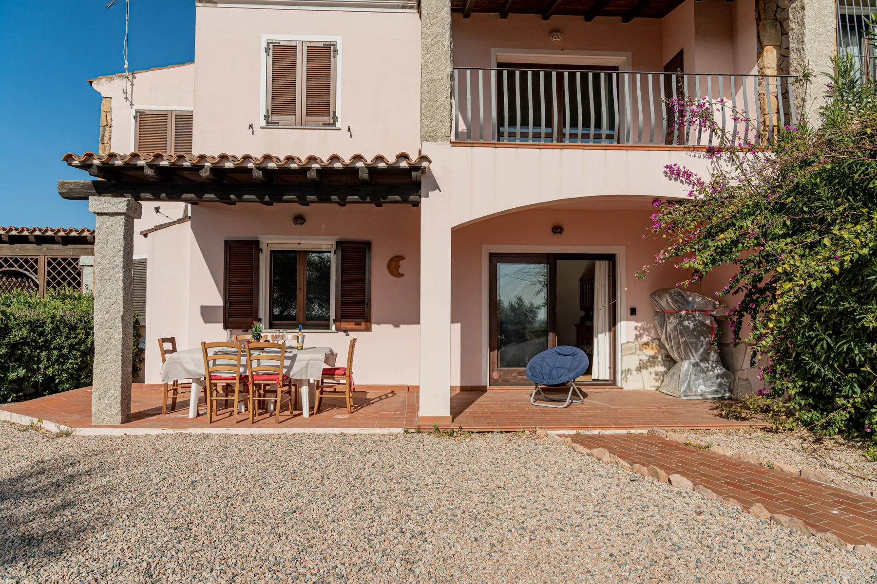 Una casa clara da a un patio con asientos al aire libre y una puerta corrediza de vidrio.