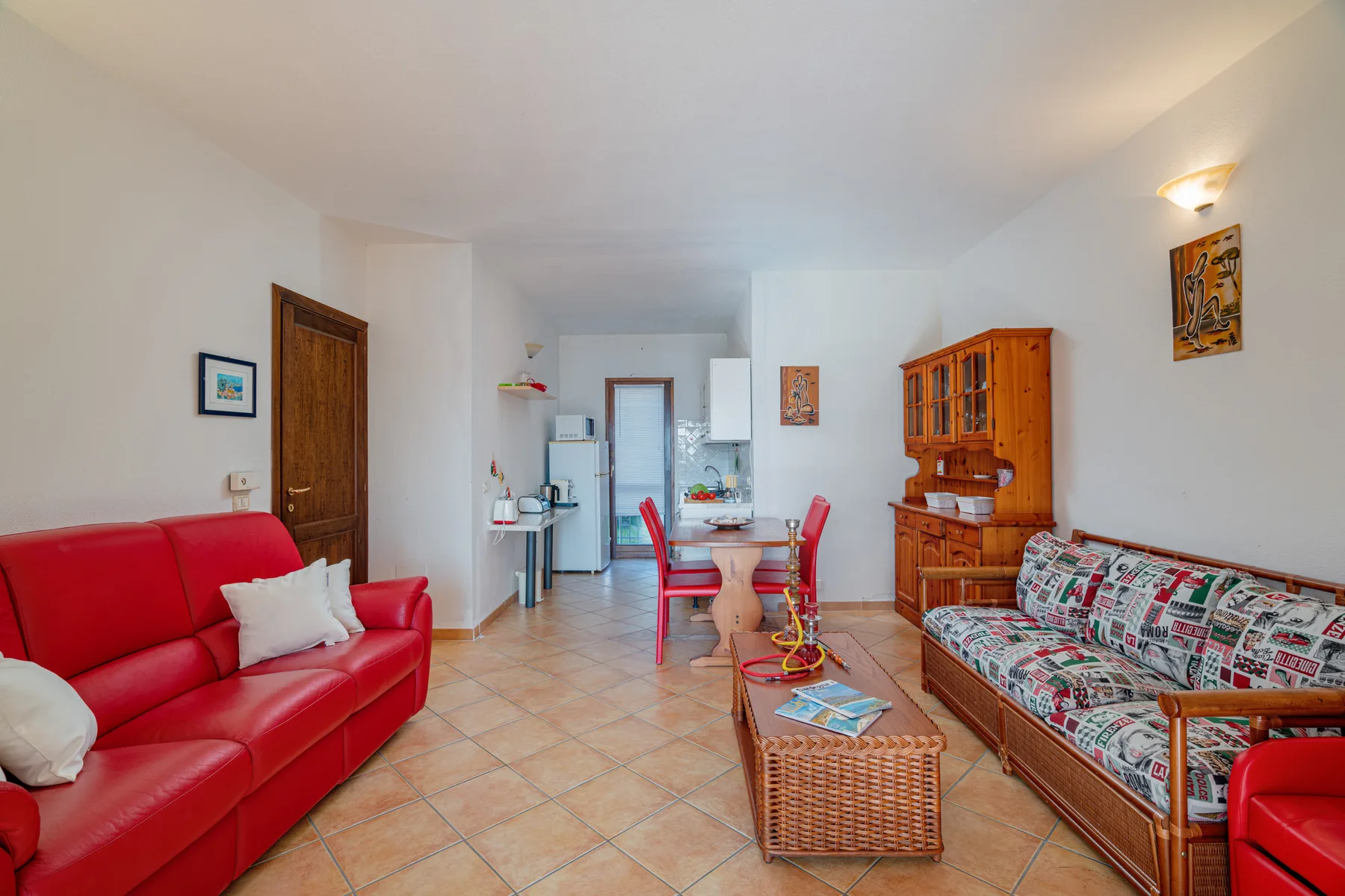 Una sala de estar con asientos rojos, un sofá estampado y una mesa de comedor.