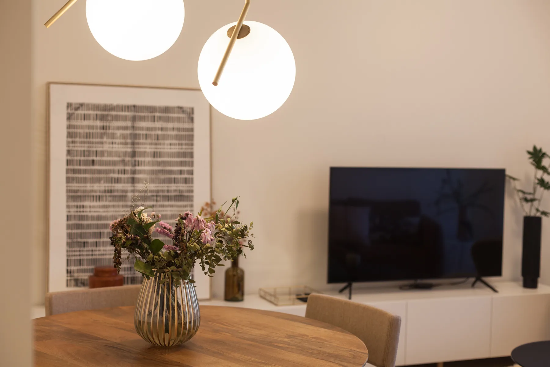 Una sala de estar con una mesa de comedor, flores y un televisor.