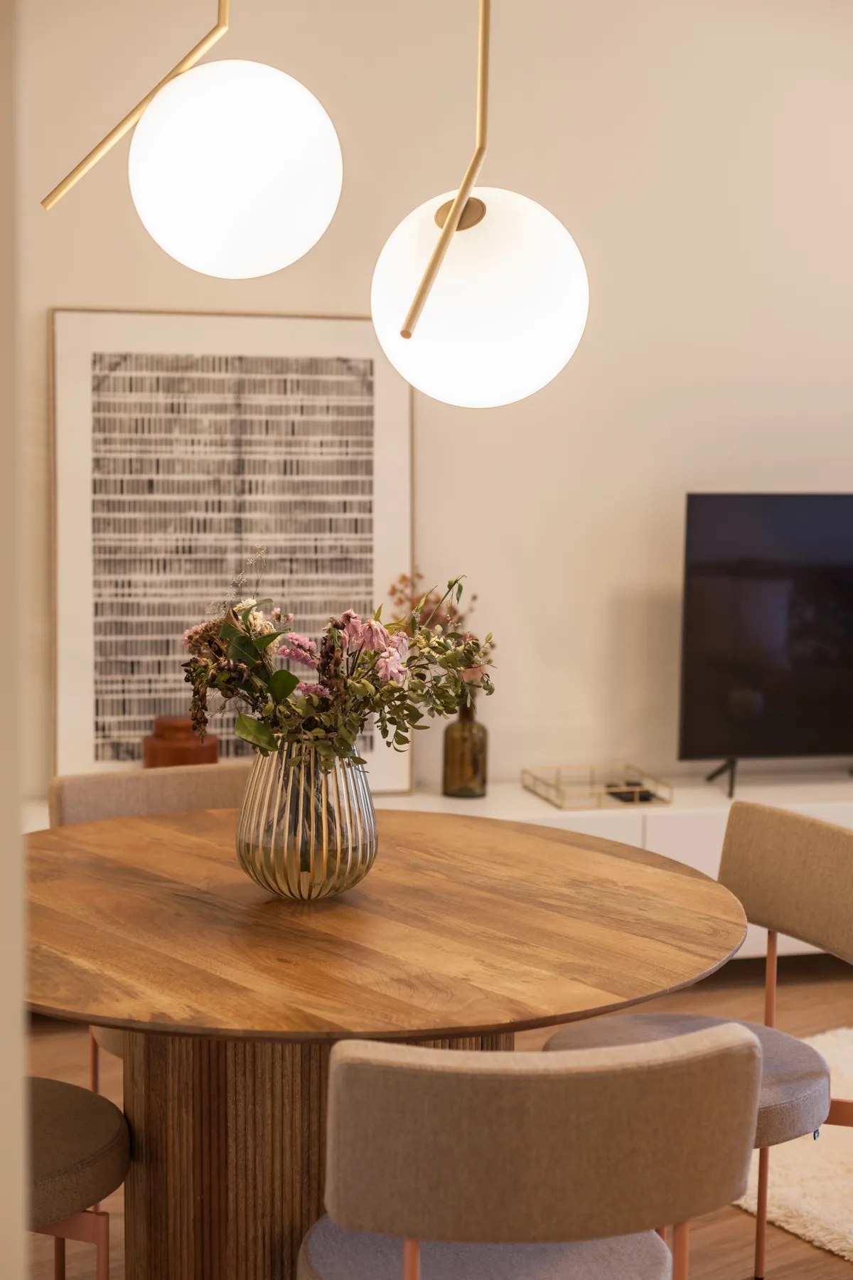 Comedor con una mesa redonda de madera y flores en un jarrón.