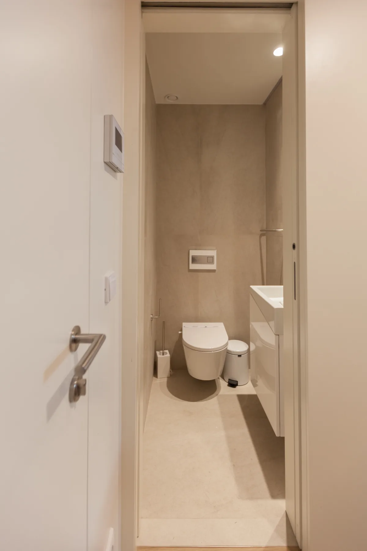Un baño con inodoro y lavabo se ve a través de la puerta abierta.