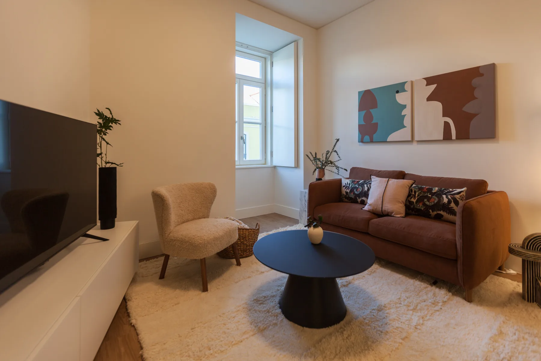 Una sala de estar con asientos alrededor de una mesa de centro y cuadros en la pared.