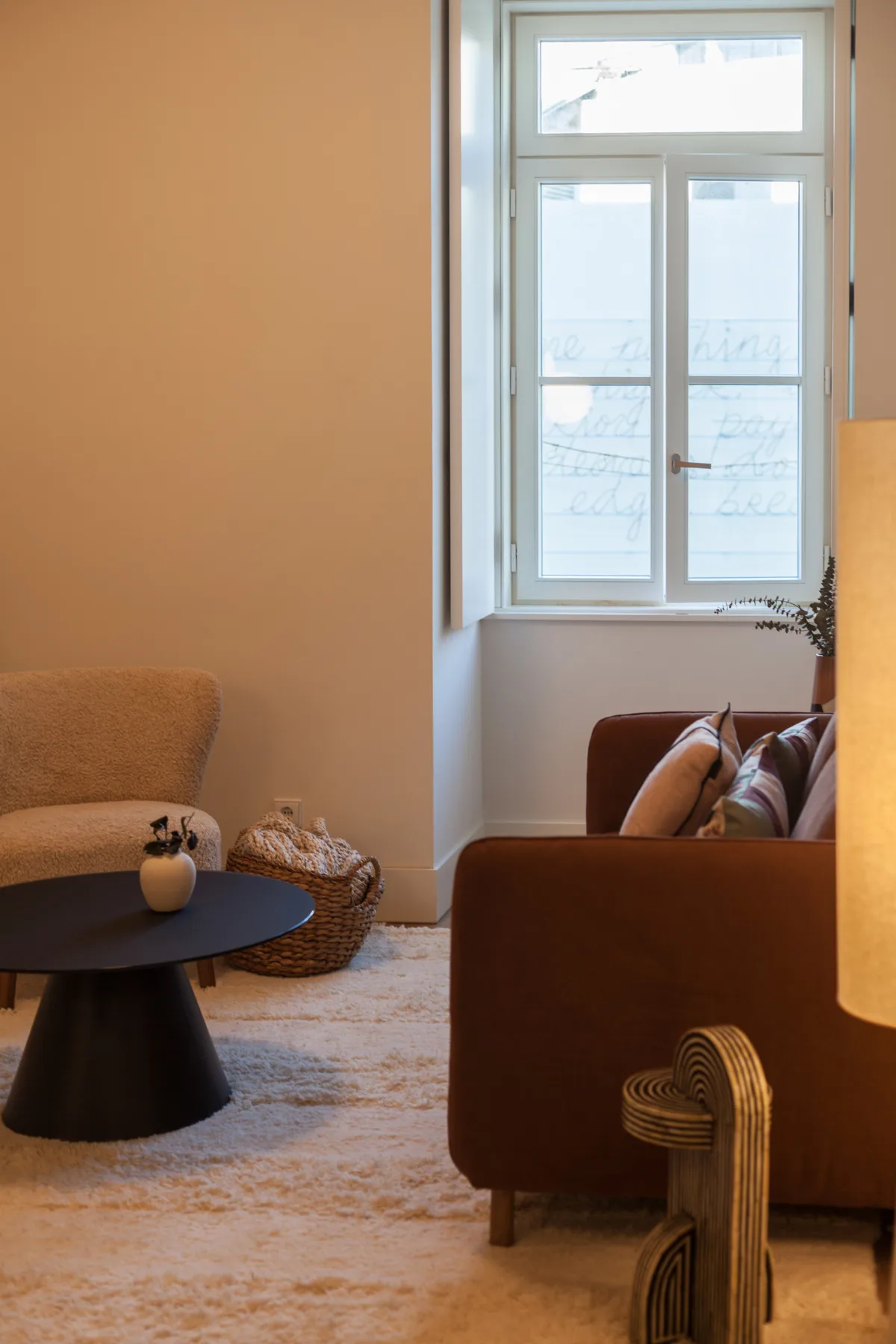 Una sala de estar con asientos alrededor de una mesa negra baja junto a una ventana alta.