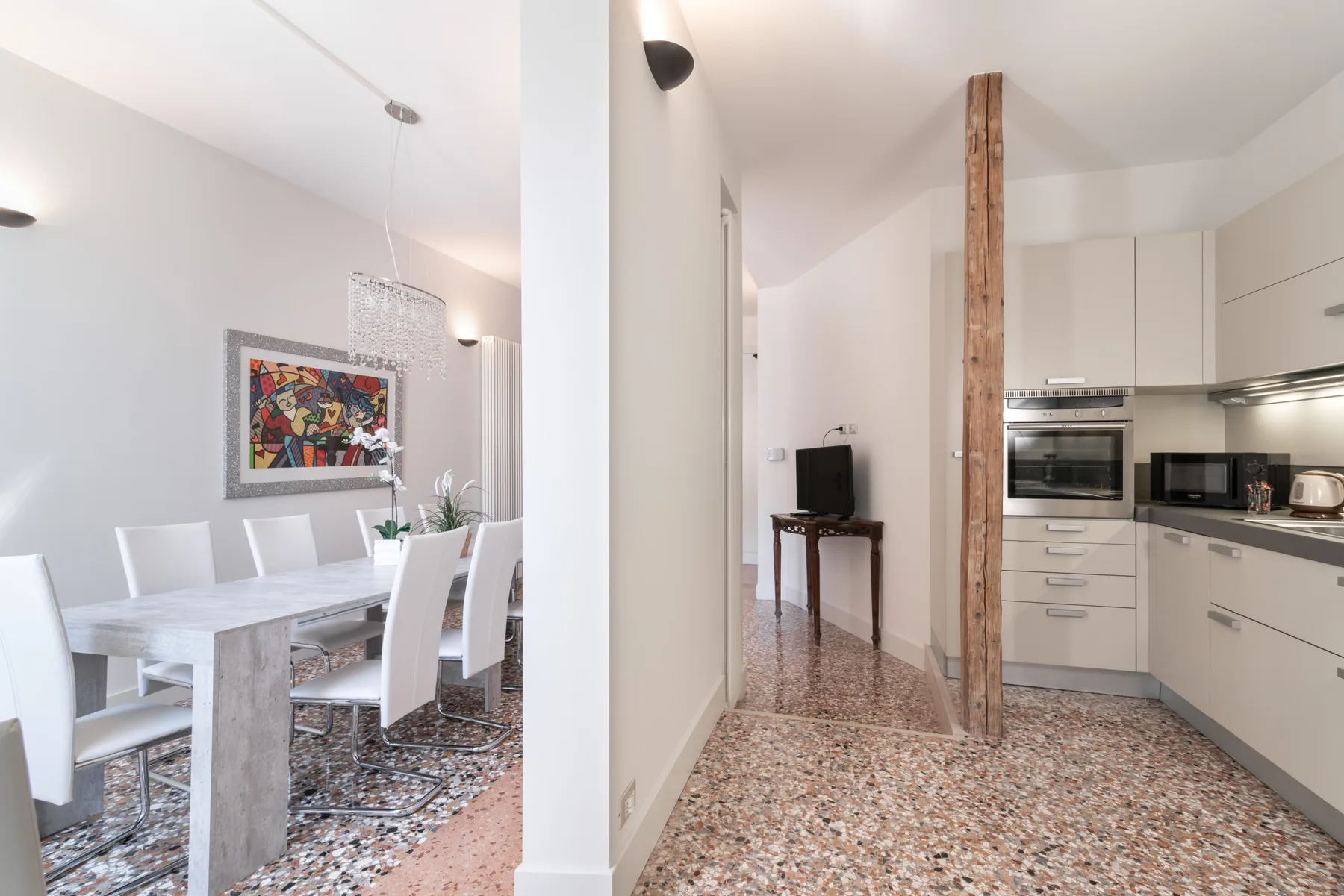Un comedor luminoso integrado con la cocina, con una mesa y electrodomésticos.