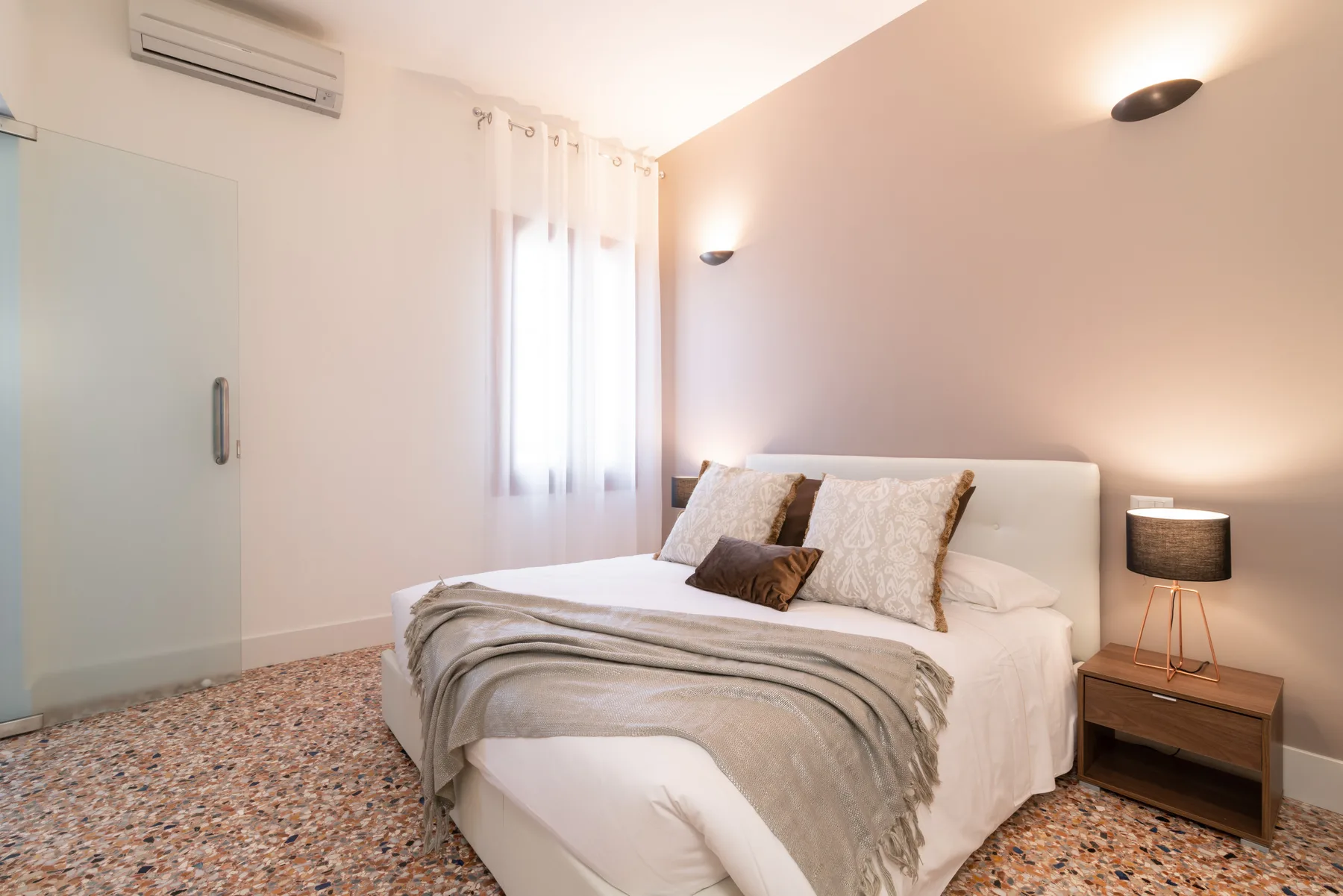 Un dormitorio con una cama bien tendida y ropa de cama en tonos neutros.