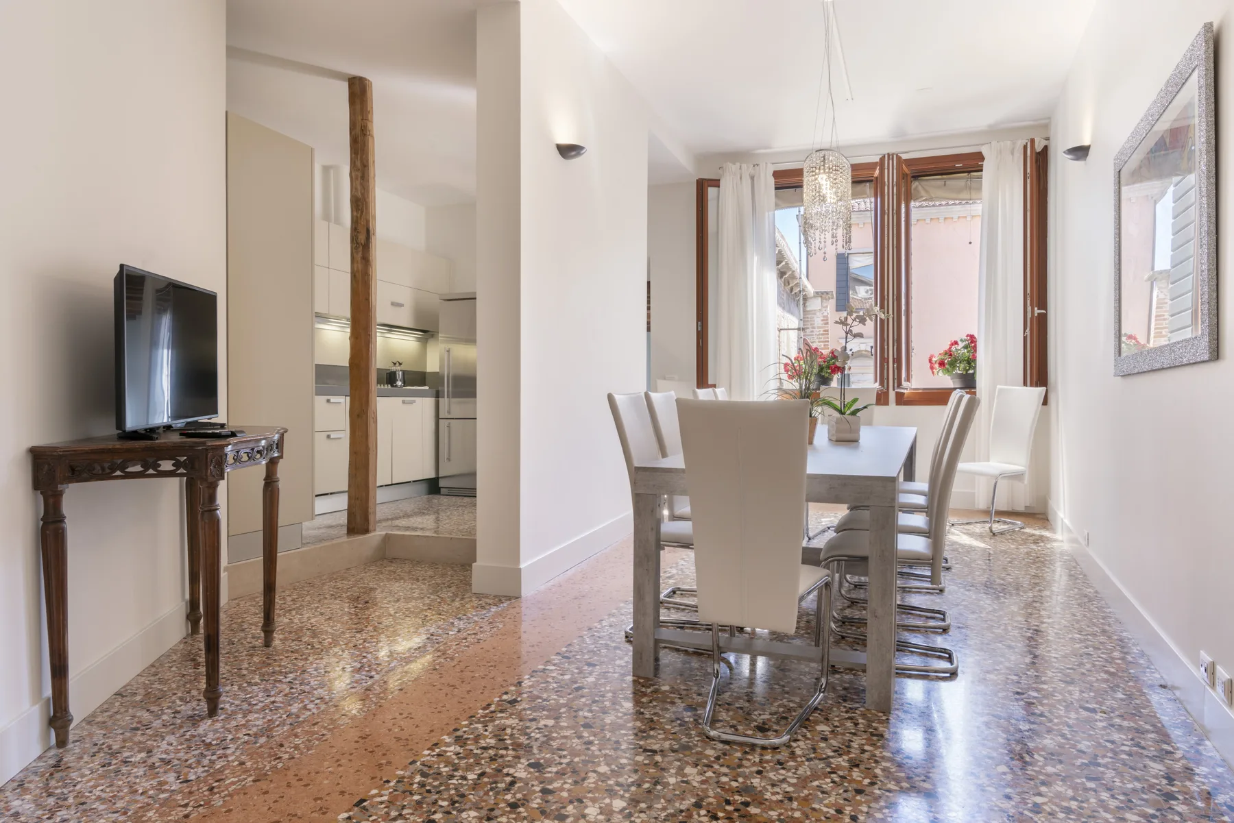 Un comedor luminoso con una mesa y sillas junto a grandes ventanas.