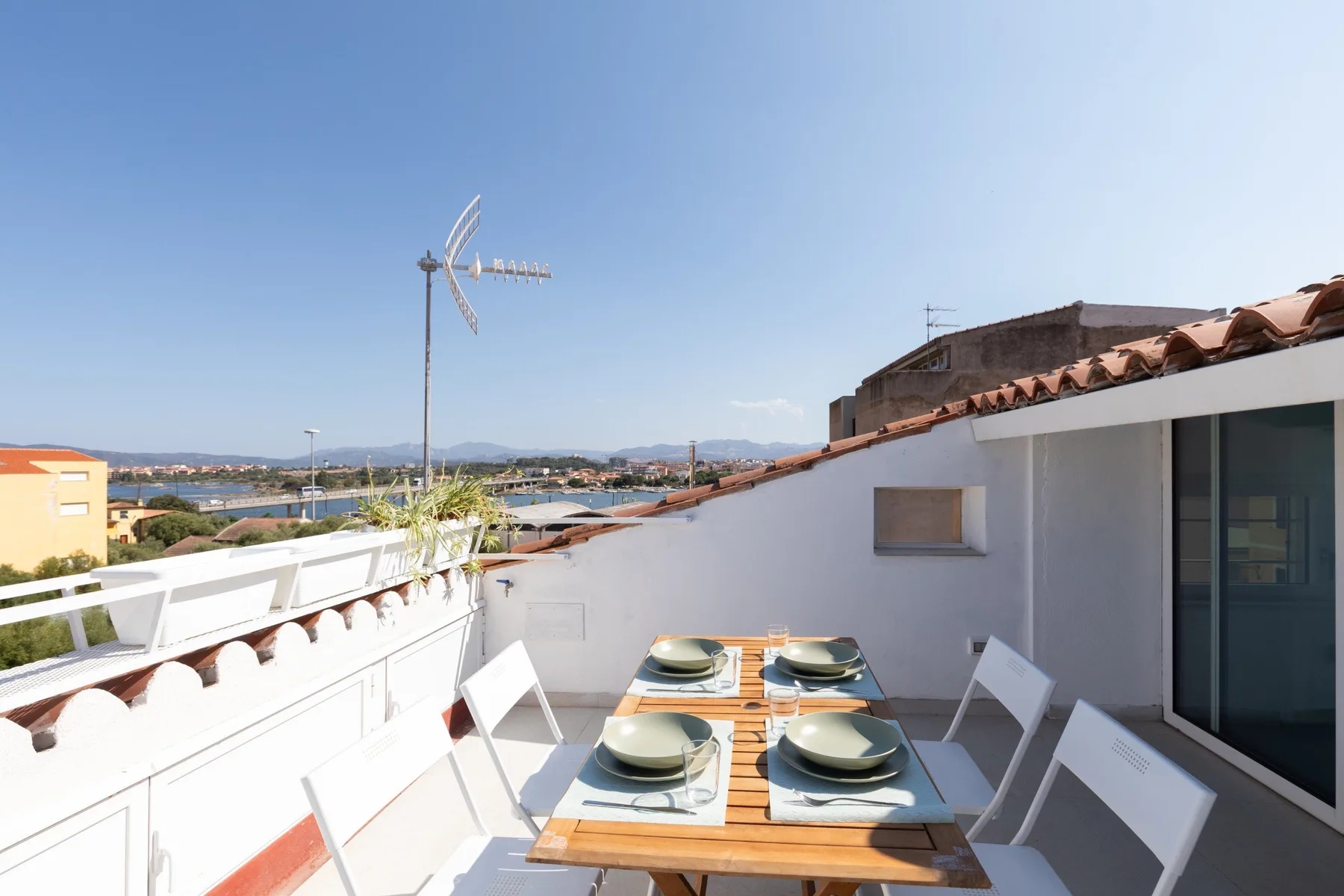 Una terraza en la azotea tiene una mesa de comedor al aire libre rodeada de asientos.