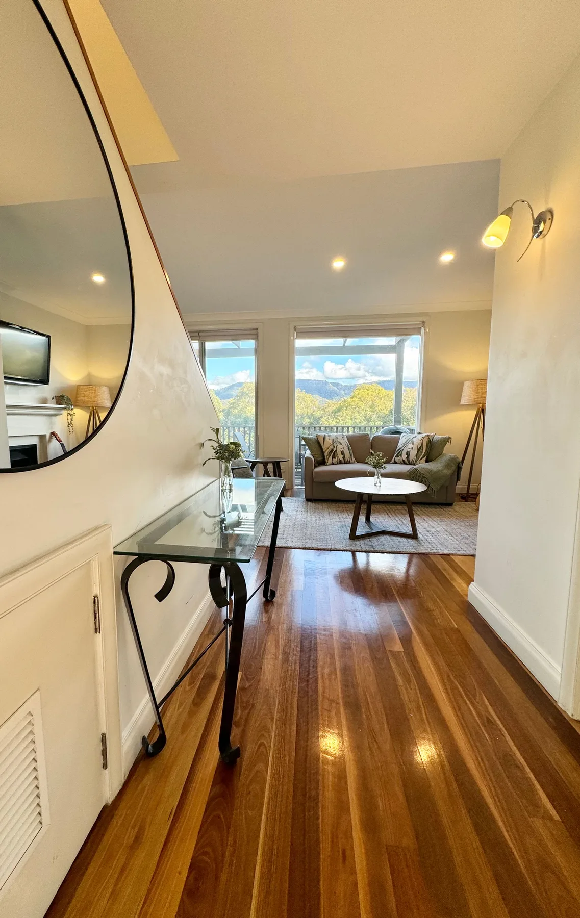 Una sala de estar con asientos y grandes ventanas con vistas a un paisaje montañoso.