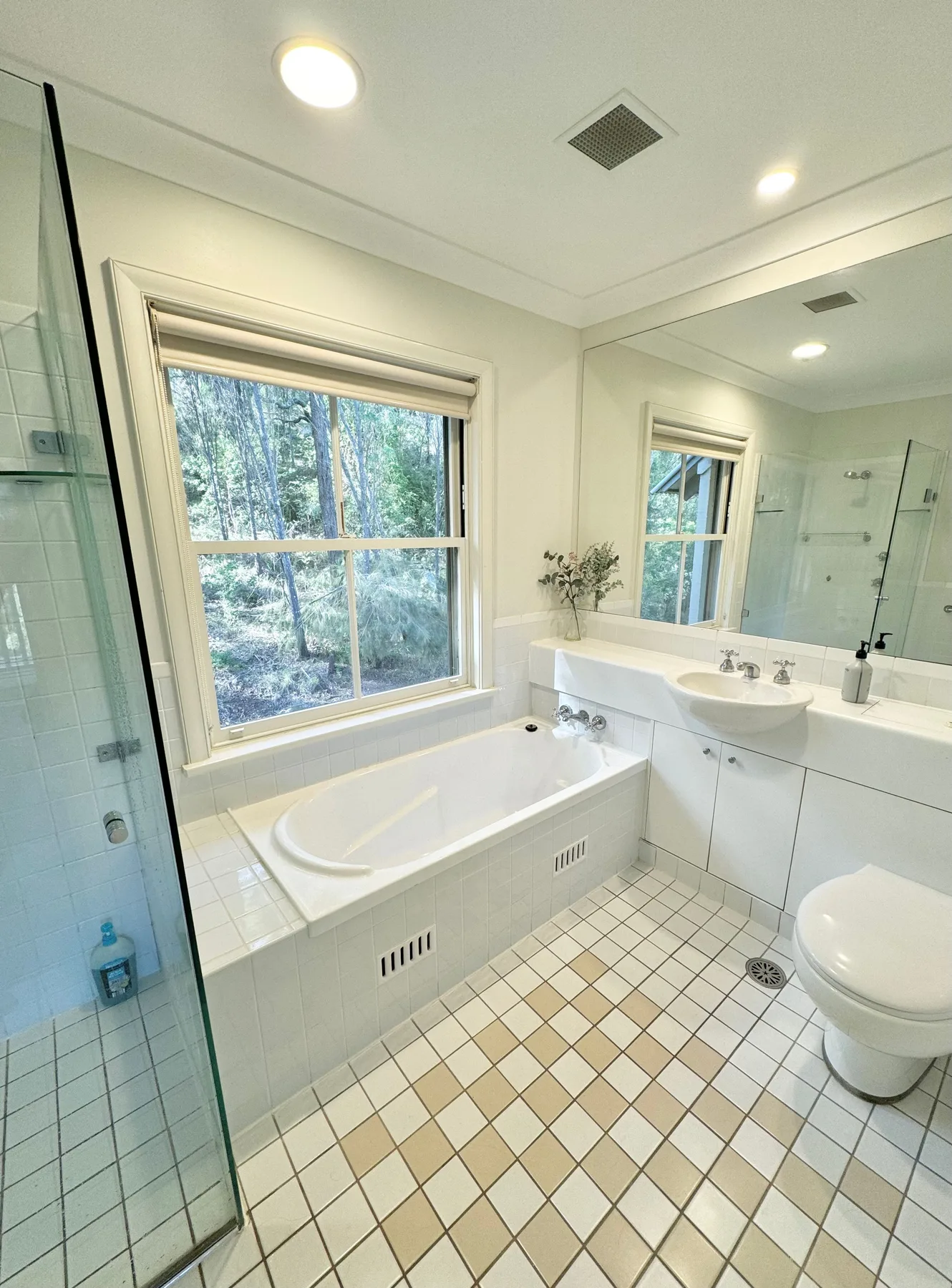 Un baño luminoso con bañera, suelo de baldosas y una ventana grande.