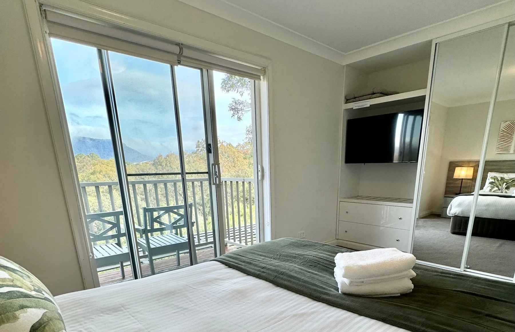 Un dormitorio con una cama junto a puertas corredizas de vidrio que dan a un balcón.