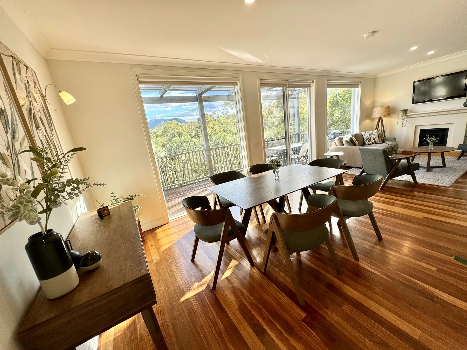 Una luminosa sala-comedor de planta abierta con grandes ventanas que dan a los árboles.