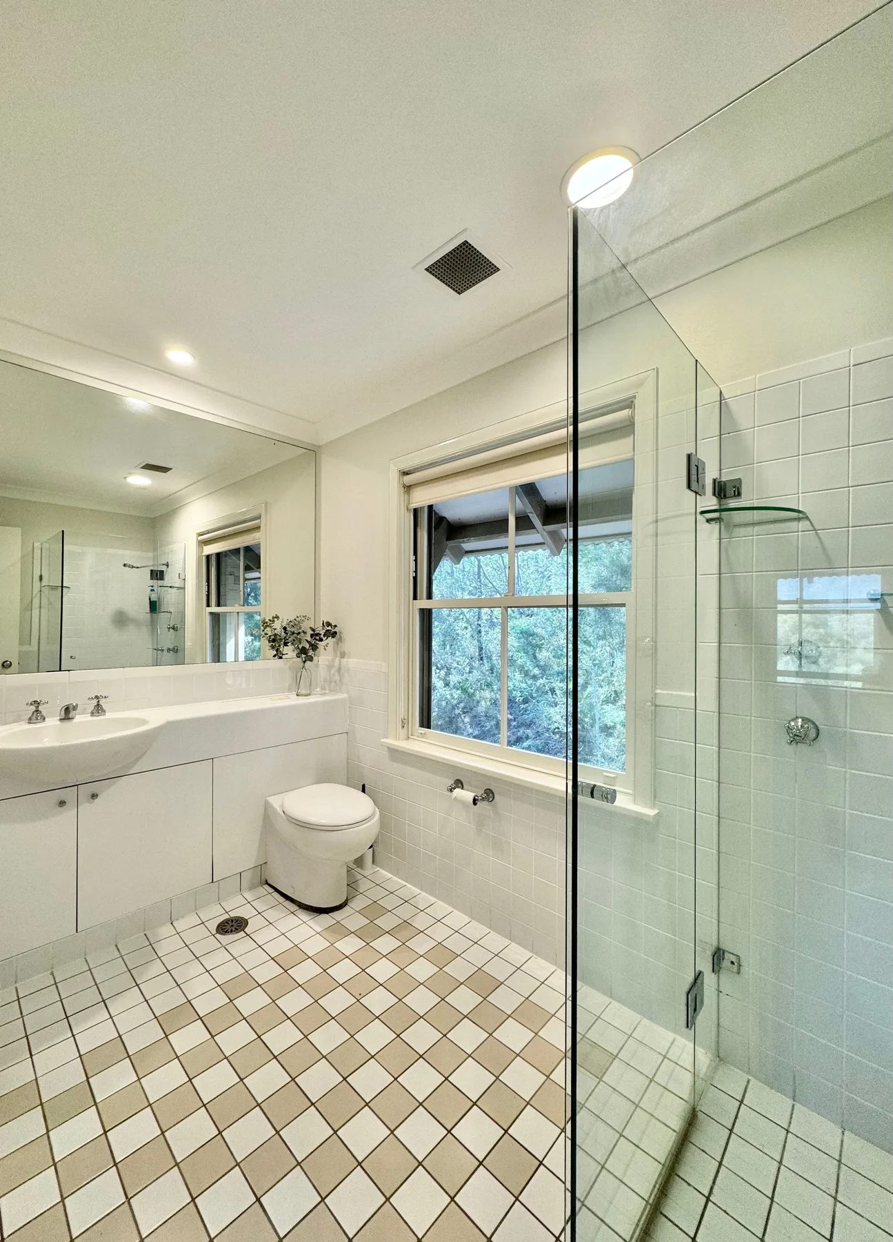 Un baño luminoso con lavabo, inodoro y ducha de vidrio.