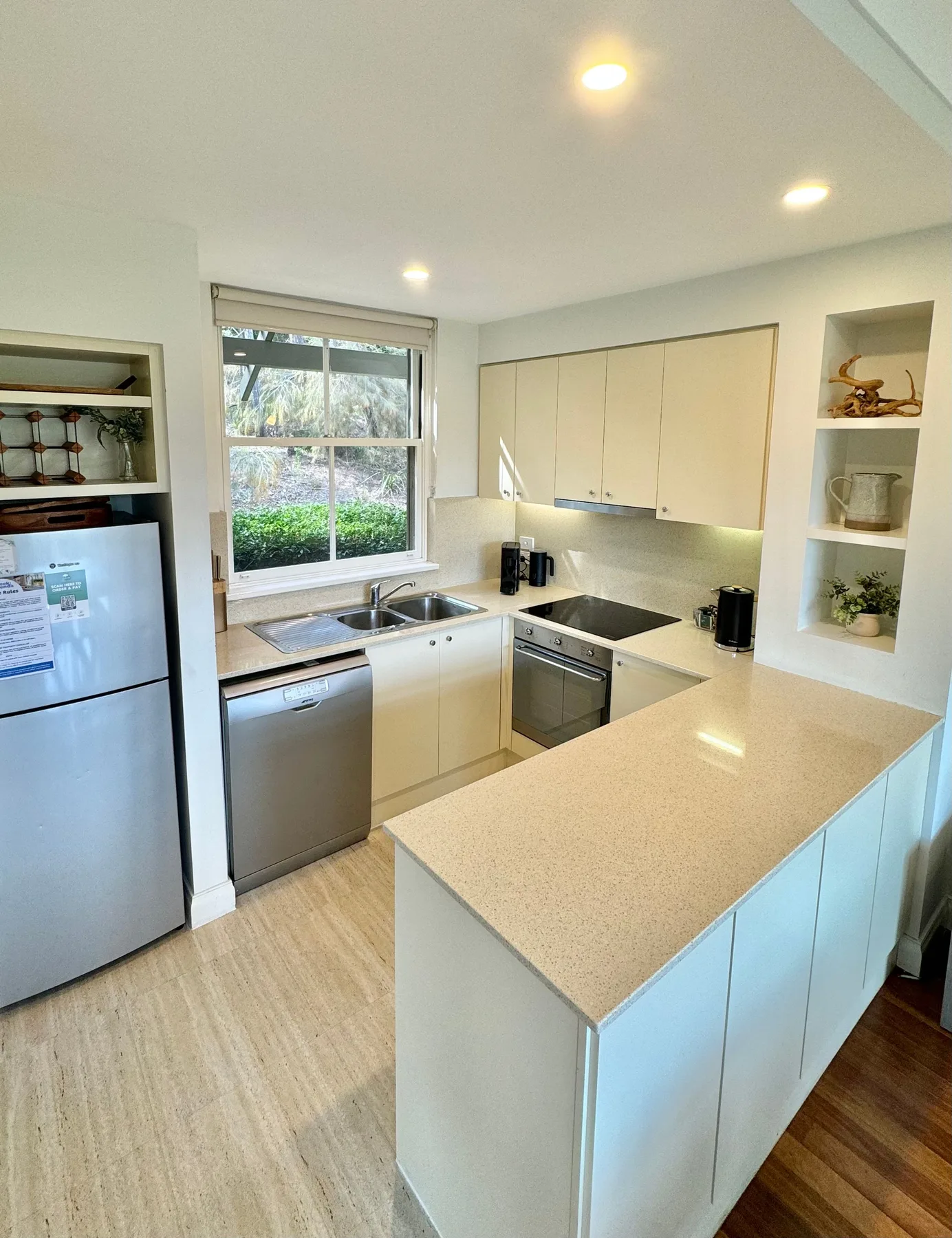 Una cocina luminosa con gabinetes claros, un fregadero y una isla central.