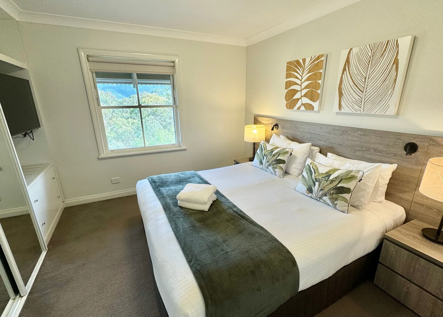 Un dormitorio con una cama bien tendida, cojines decorativos y una ventana.