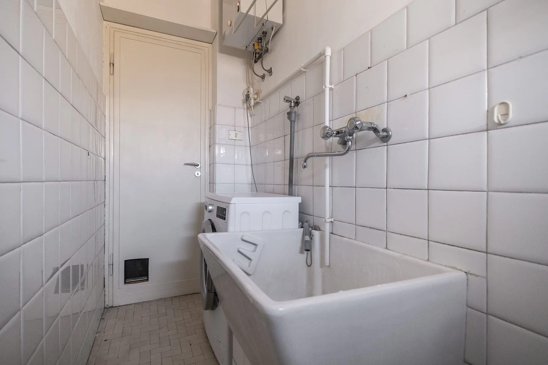 A tiled bathroom with a bathtub, wall-mounted faucet, and closed door.