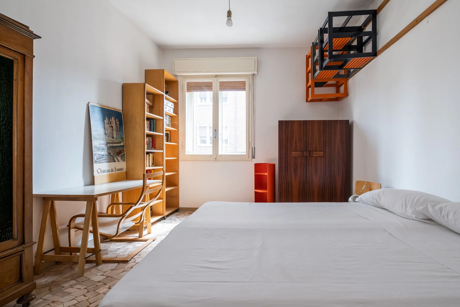 A bedroom with a large bed, a desk, and a window.