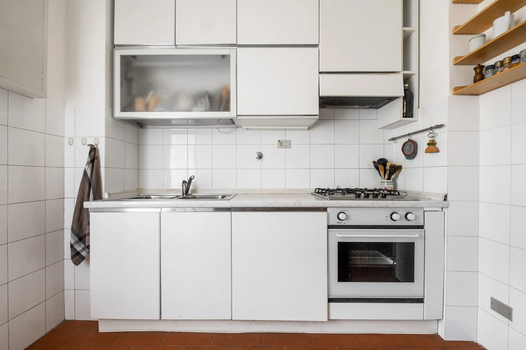 A bright kitchen with white cabinets, a sink, and a stove.