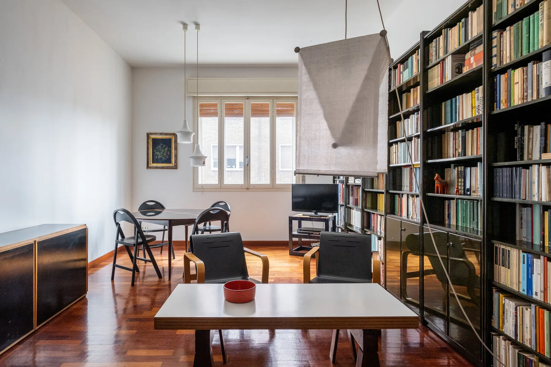 A study with tall bookshelves, a desk, and seating.