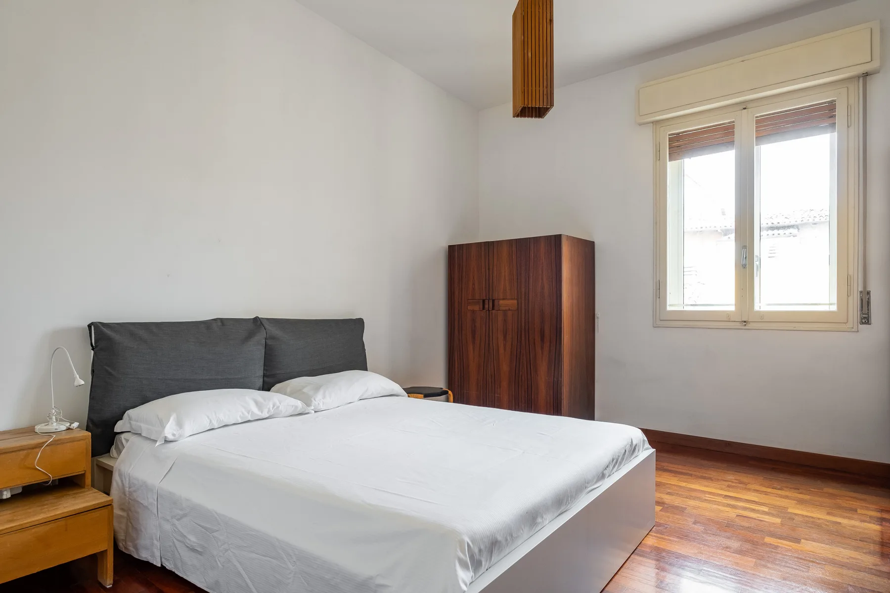 Bedroom with a bed, a wooden cabinet, and a window.