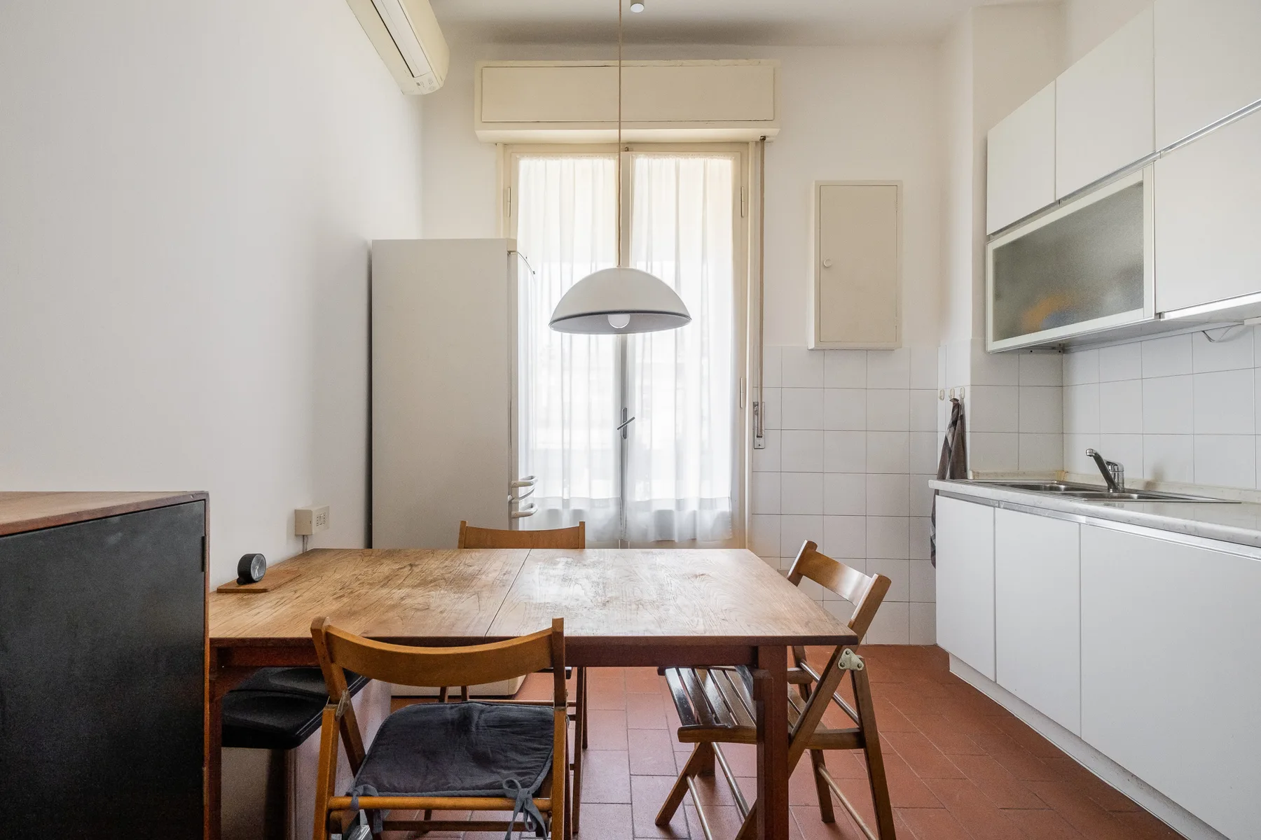 A dining area with a wooden table and chairs beside a bright window.